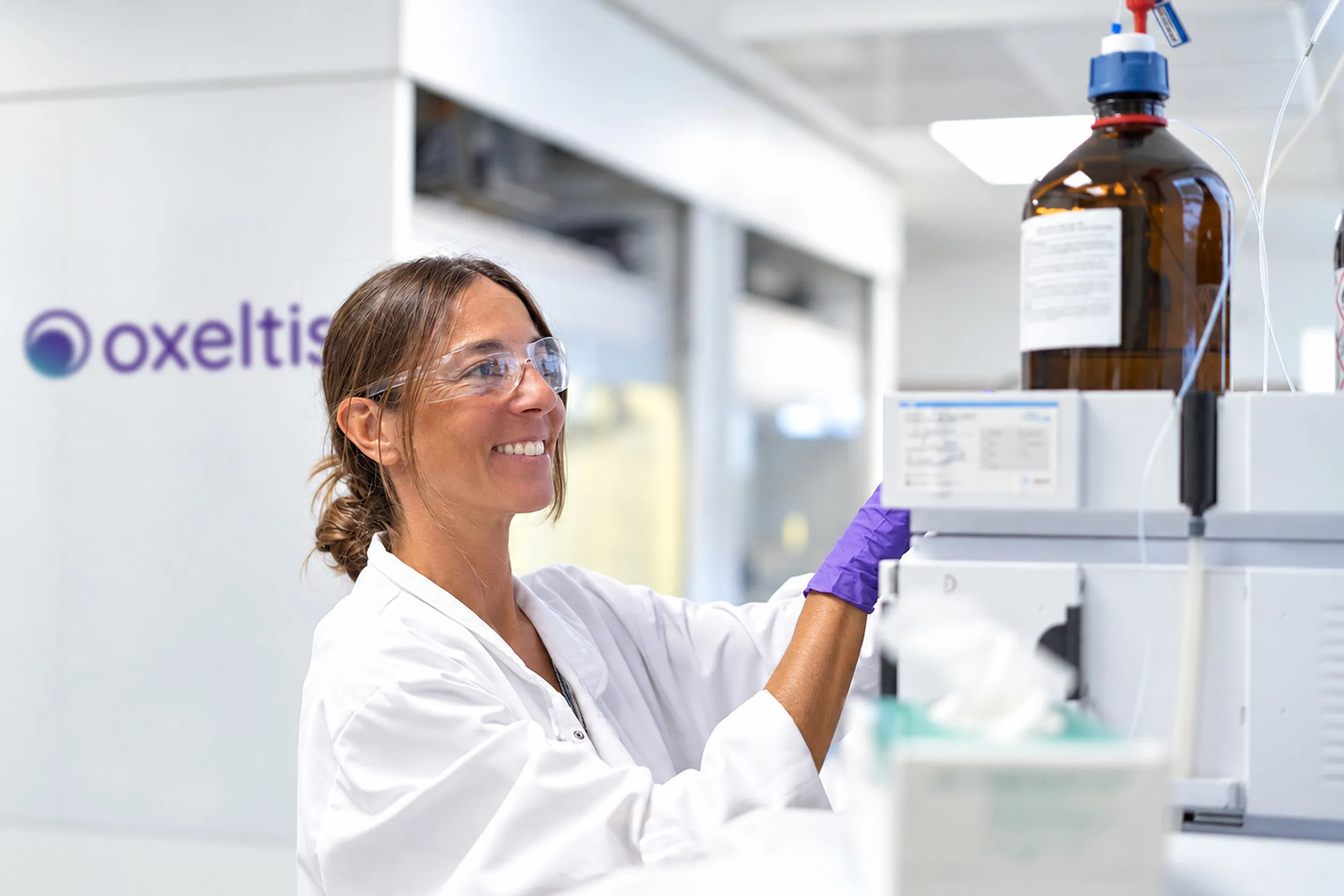 Smiling Oxeltis chemist at her workstation