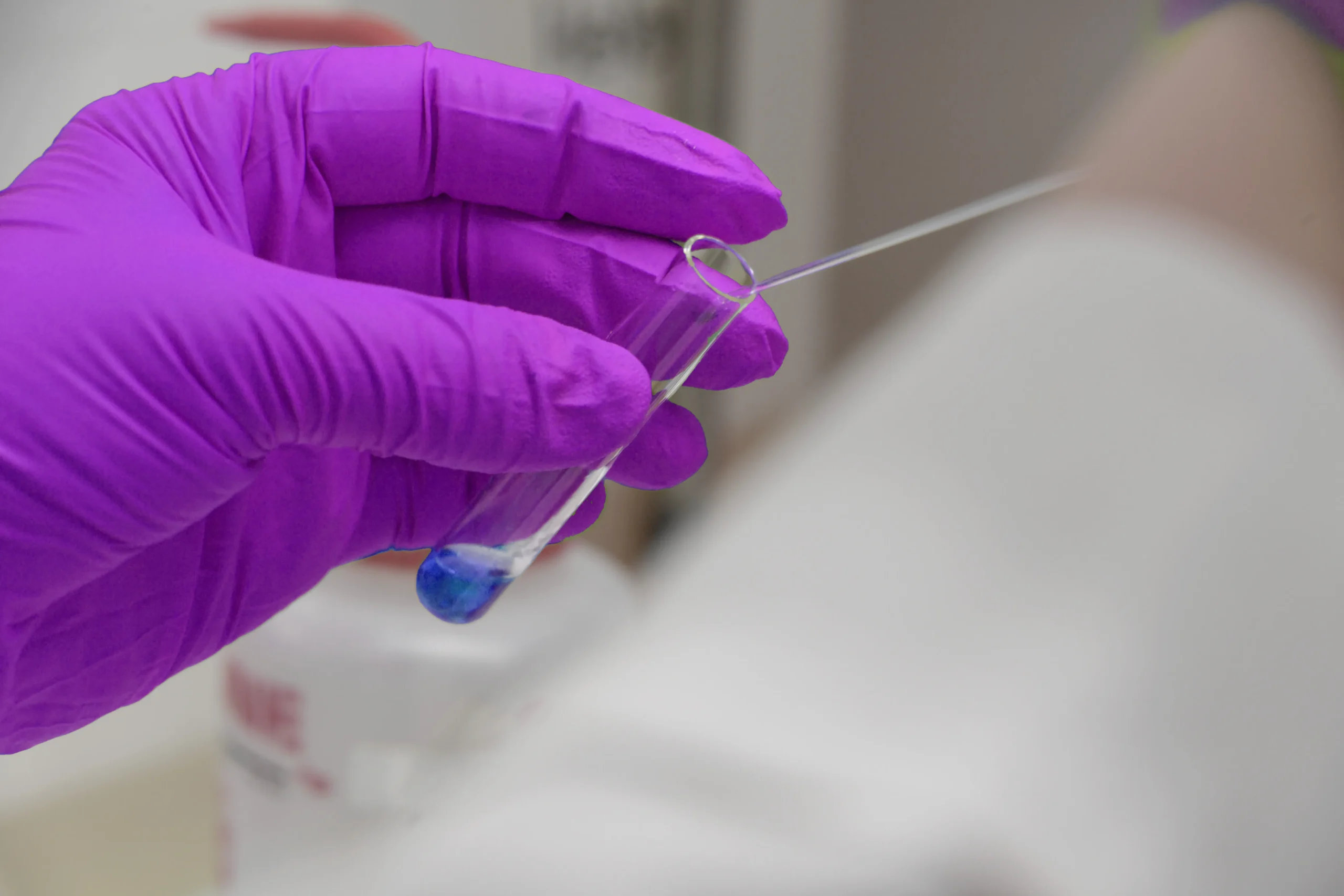 Gloved hand holding a vial during sample preparation